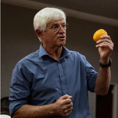 Prof. Arnold Smit holding an orange while speaking.